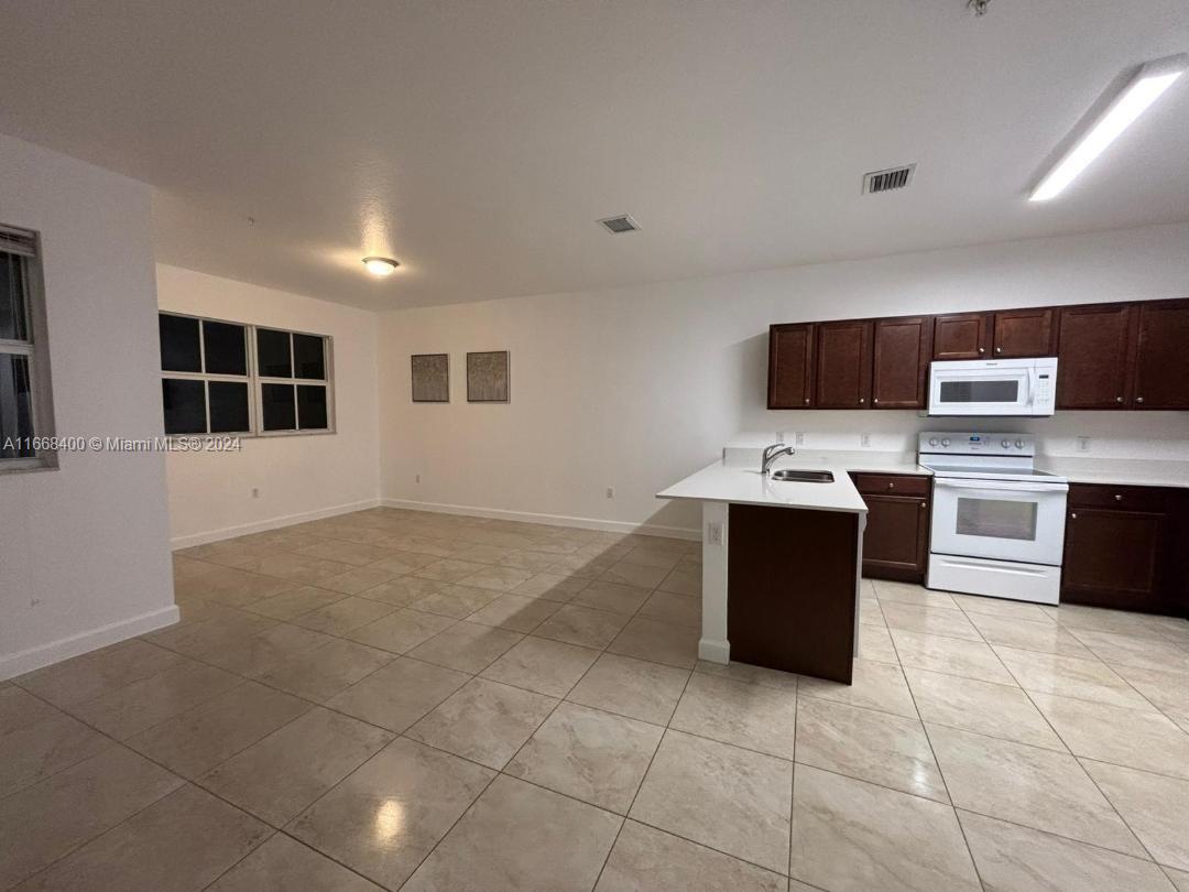 a kitchen with a sink a counter top space appliances and cabinets