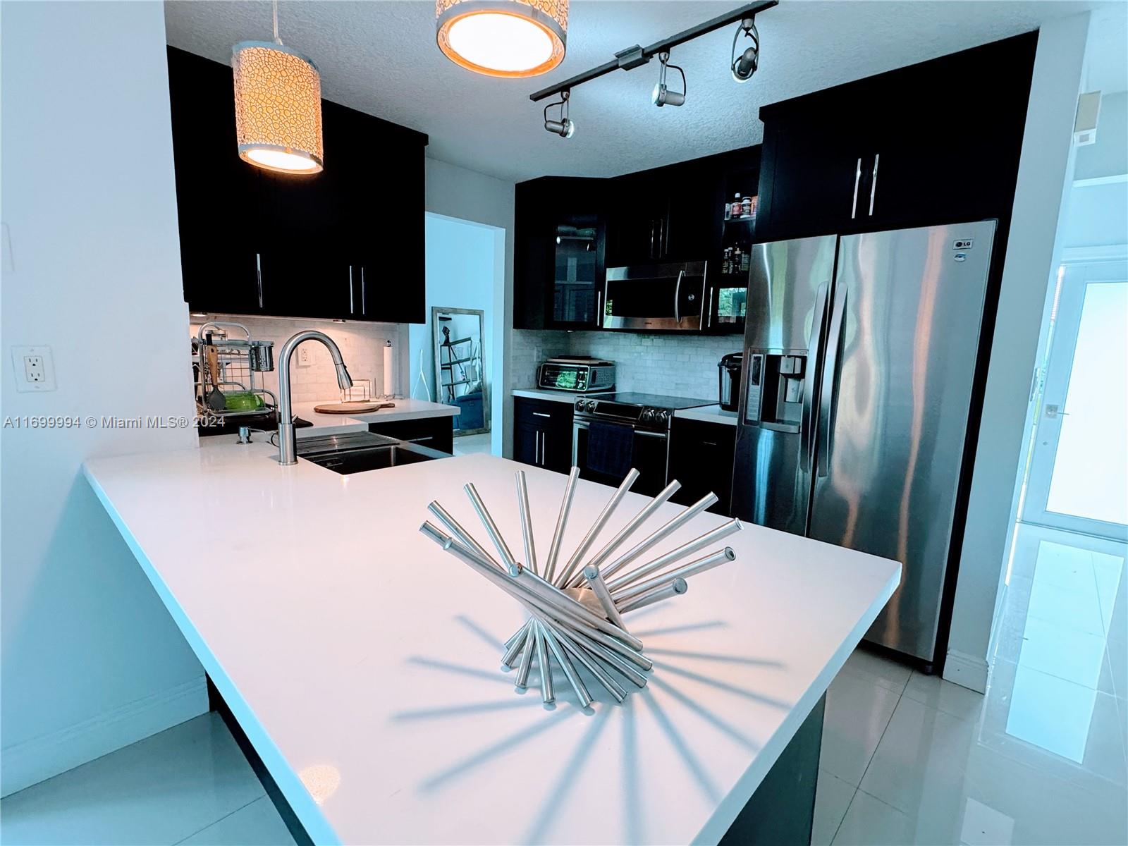 a kitchen with a refrigerator a stove and a sink with wooden floor