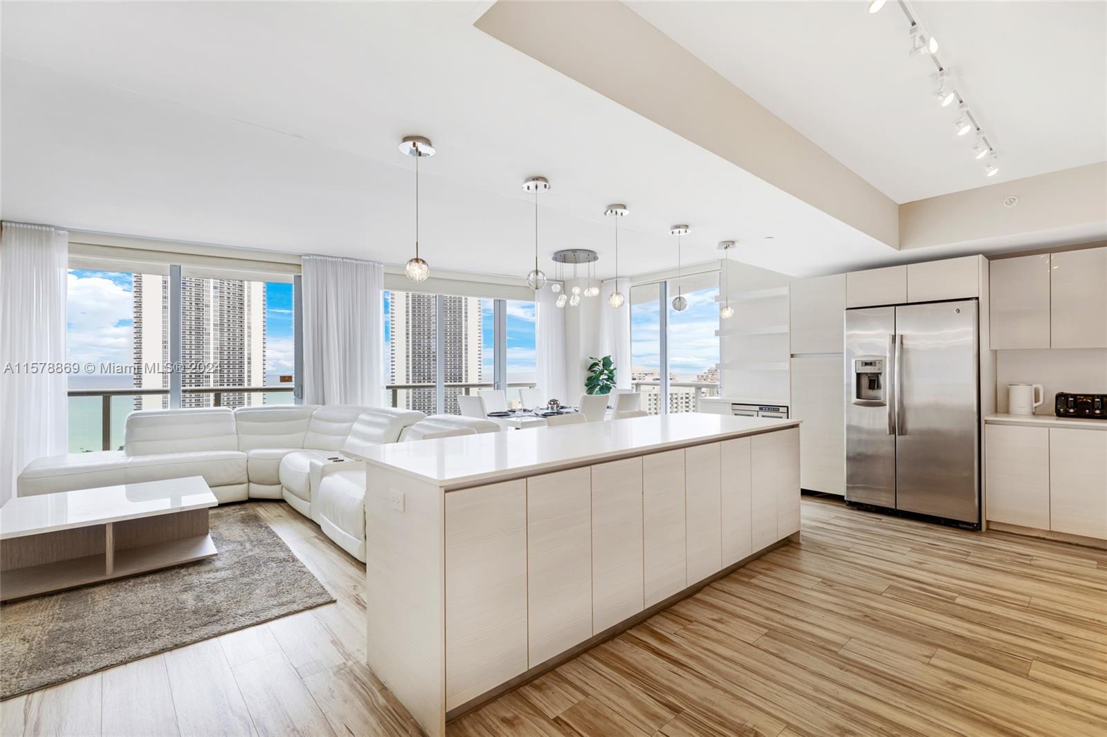 a large white kitchen with a large window and stainless steel appliances