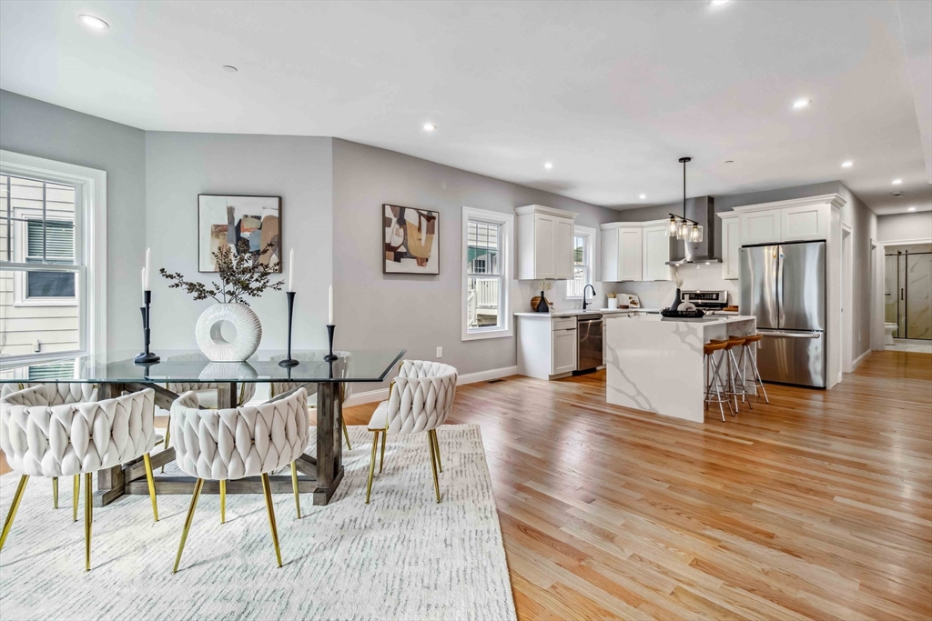 a living room with stainless steel appliances granite countertop furniture wooden floor and a kitchen view