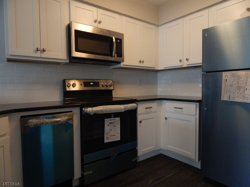 a kitchen with stainless steel appliances granite countertop a stove a microwave and a white cabinets