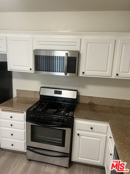 a kitchen with white cabinets and black appliances