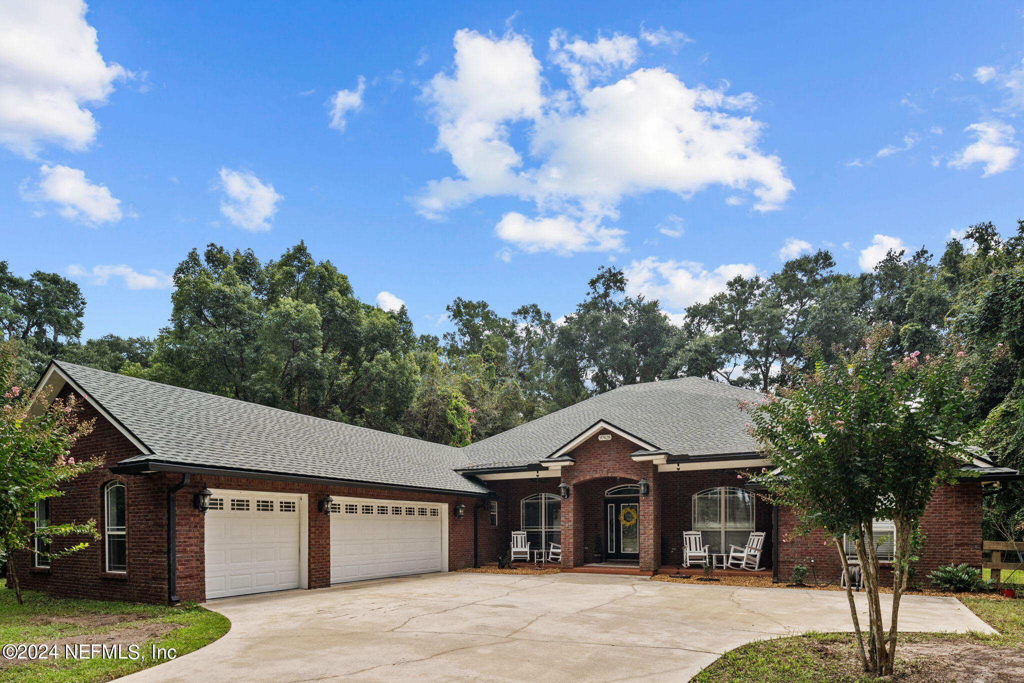 a front view of a house with a garden and trees