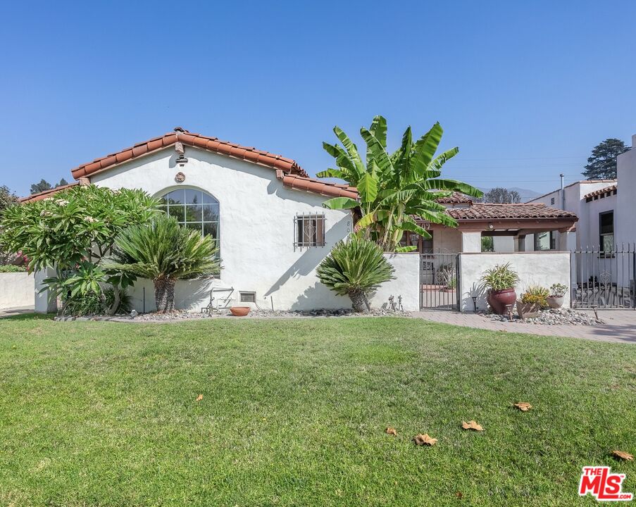 a view of a house with a yard and potted plants