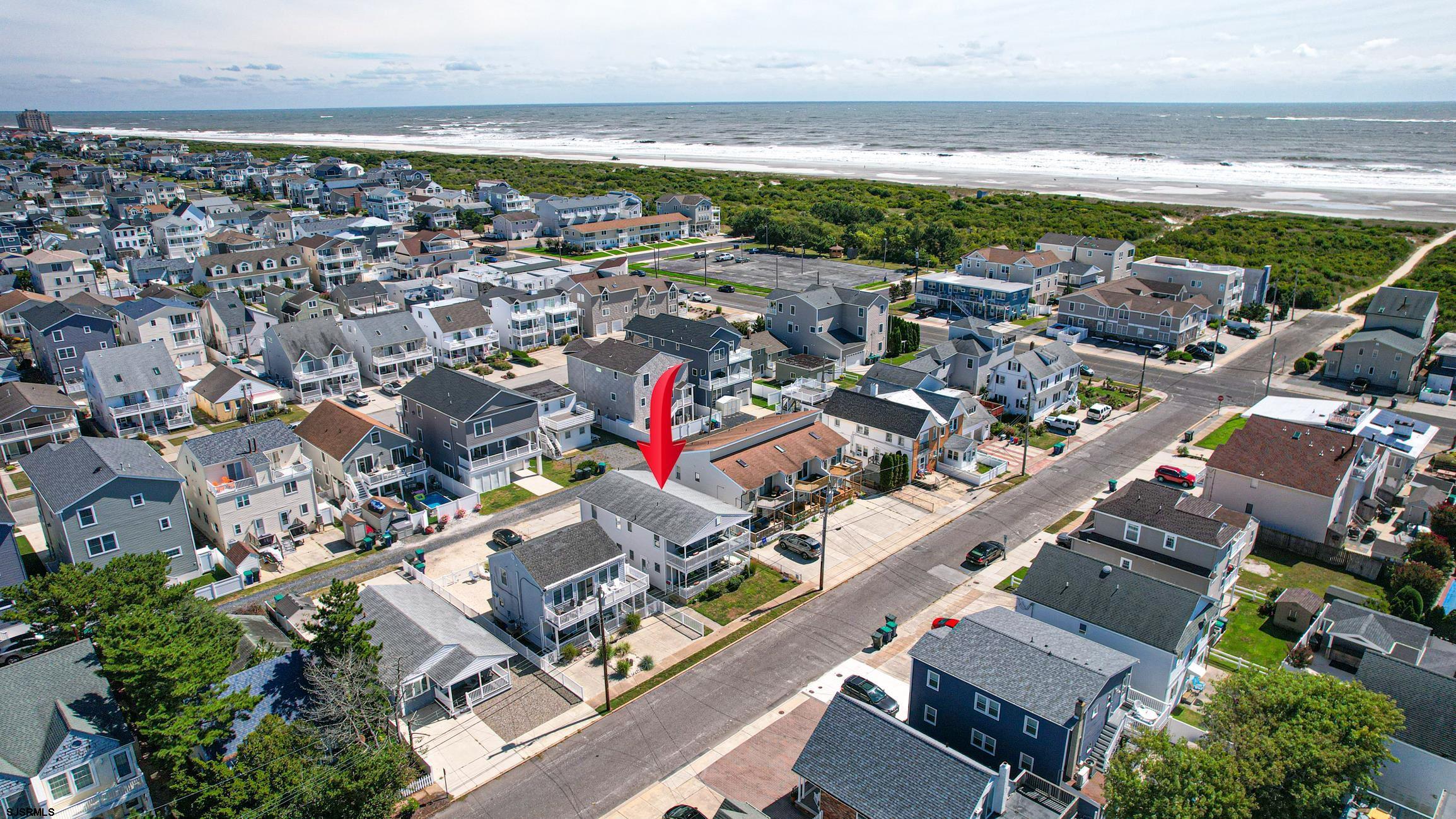 an aerial view of a city with lots of residential buildings and ocean view in back