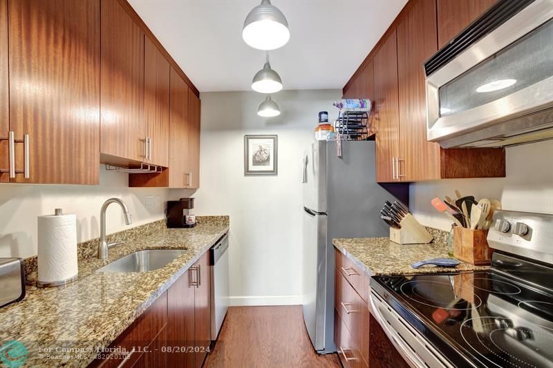 a kitchen with stainless steel appliances granite countertop a sink stove and refrigerator