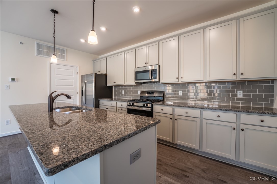 a kitchen with stainless steel appliances granite countertop a sink a stove and white cabinets