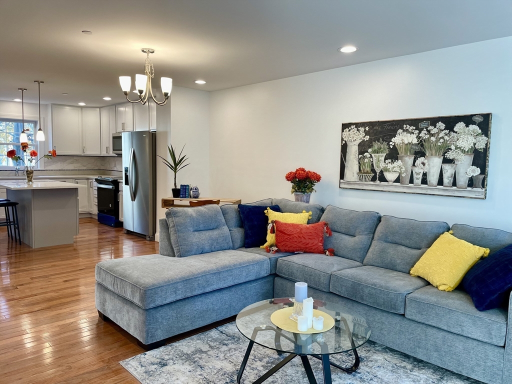 a living room with furniture kitchen view and a chandelier