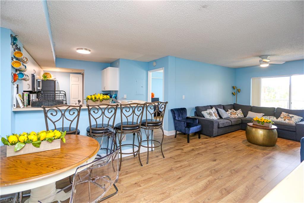 a living room with furniture kitchen view and a wooden floor