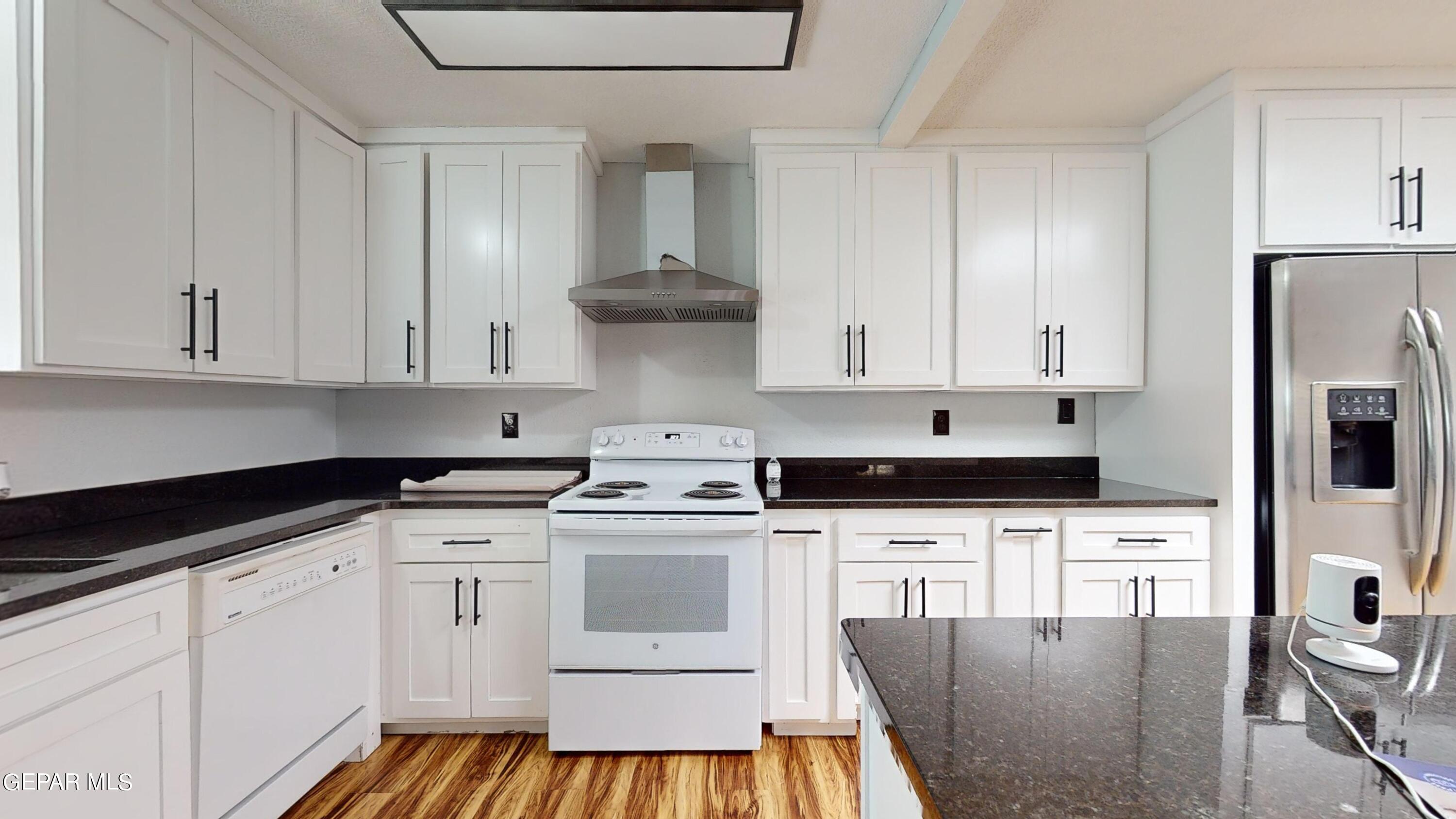 a kitchen with granite countertop a sink stove and white cabinets