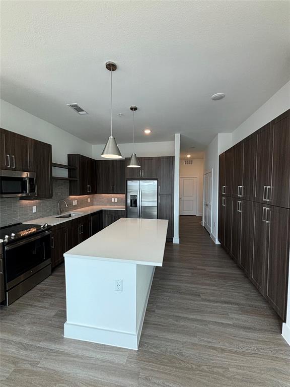 a large kitchen with stainless steel appliances kitchen island a large counter top and wooden floors