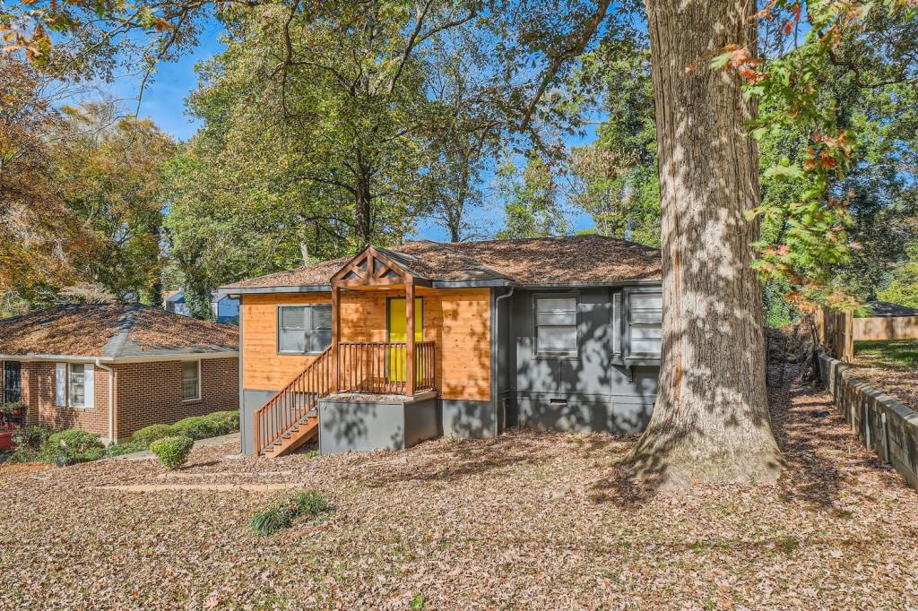 a view of a house with a small yard and large tree