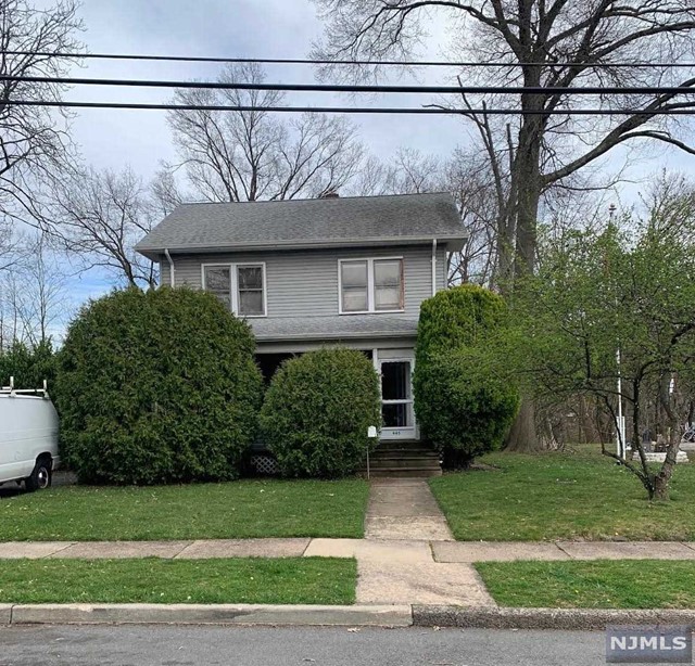 a view of a house with a yard plants and large tree