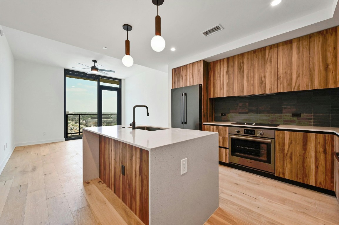 a kitchen with kitchen island granite countertop a stove top oven a sink and dishwasher with wooden floor