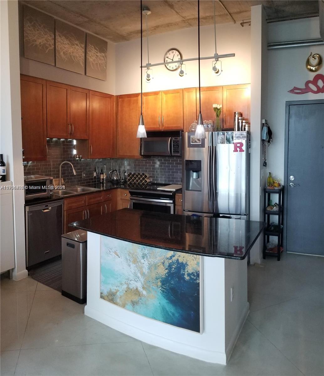 a kitchen with stainless steel appliances granite countertop a sink and a refrigerator