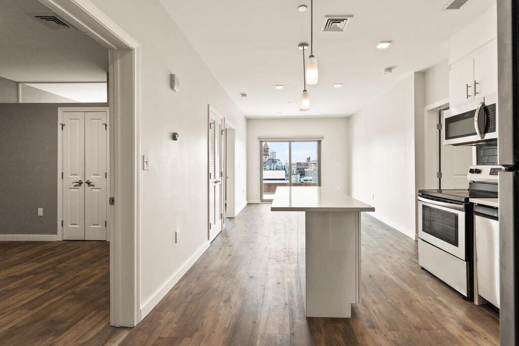 a view of a kitchen center island wooden floor and stainless steel appliances