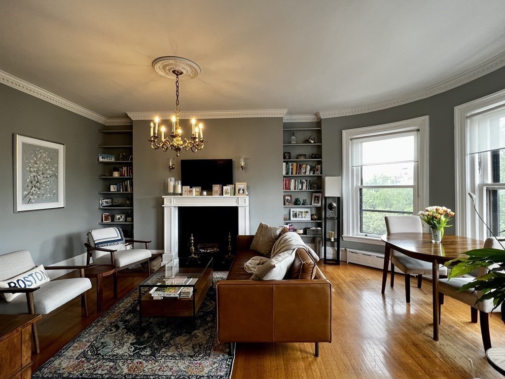 a living room with furniture a fireplace and a dining table with wooden floor