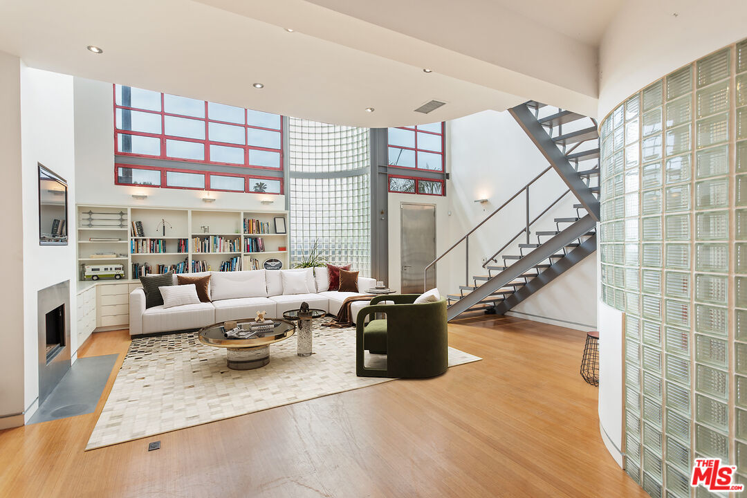 a living room with furniture large windows and wooden floor