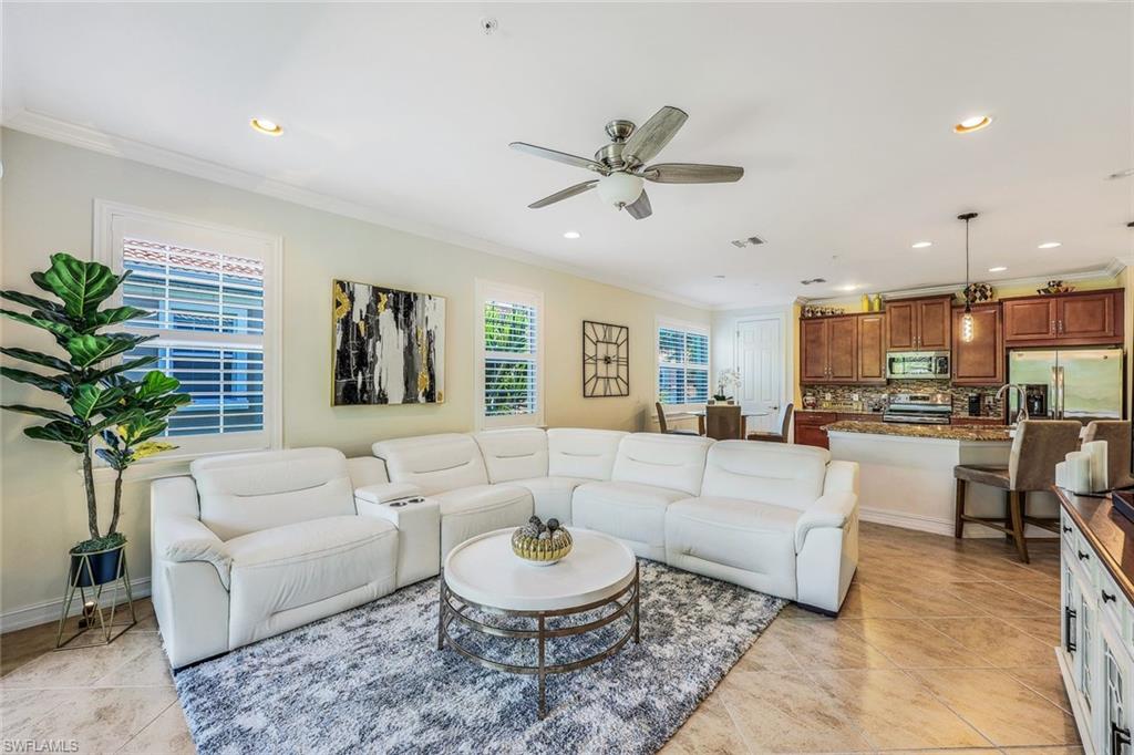 Living room featuring ceiling fan, ornamental molding, and light tile floors