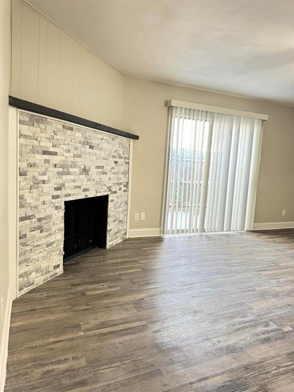 a view of empty room with wooden floor and fireplace