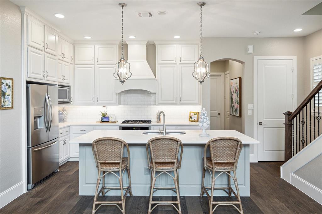 a kitchen with stainless steel appliances granite countertop a kitchen island a stove a refrigerator a oven a sink with a dining table and chairs