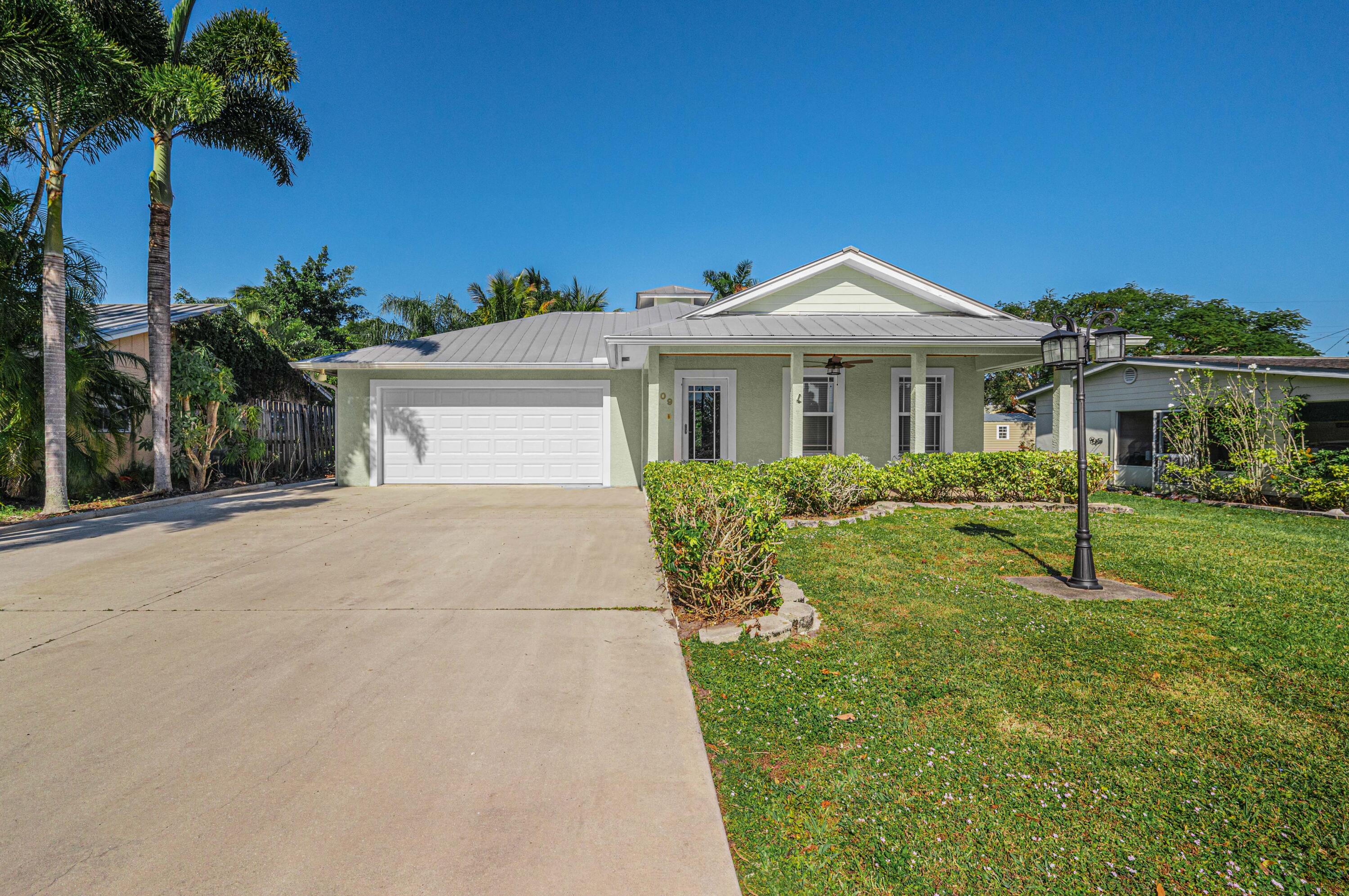 a front view of a house with a yard and palm trees