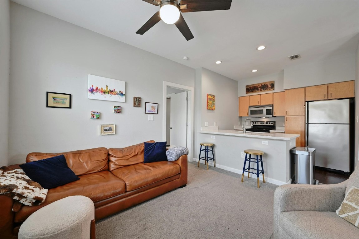 a living room with stainless steel appliances furniture stove top oven and refrigerator