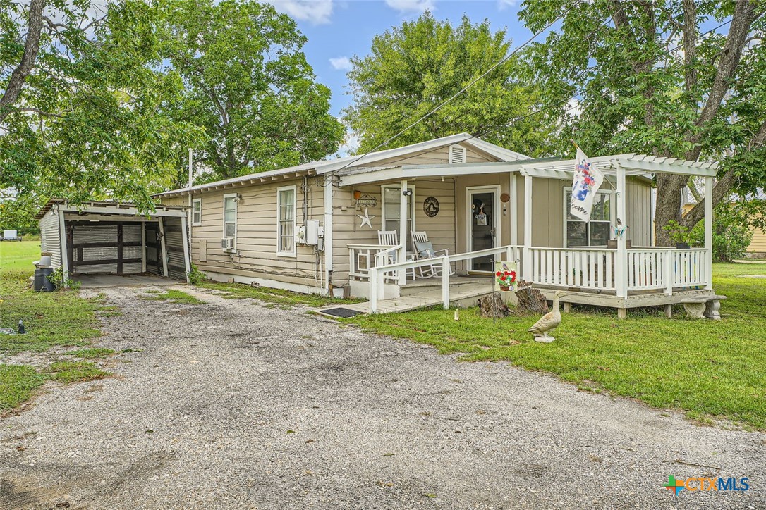 a view of a house with a yard and a large tree