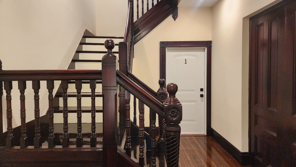 a view of a hallway with wooden floor and staircase