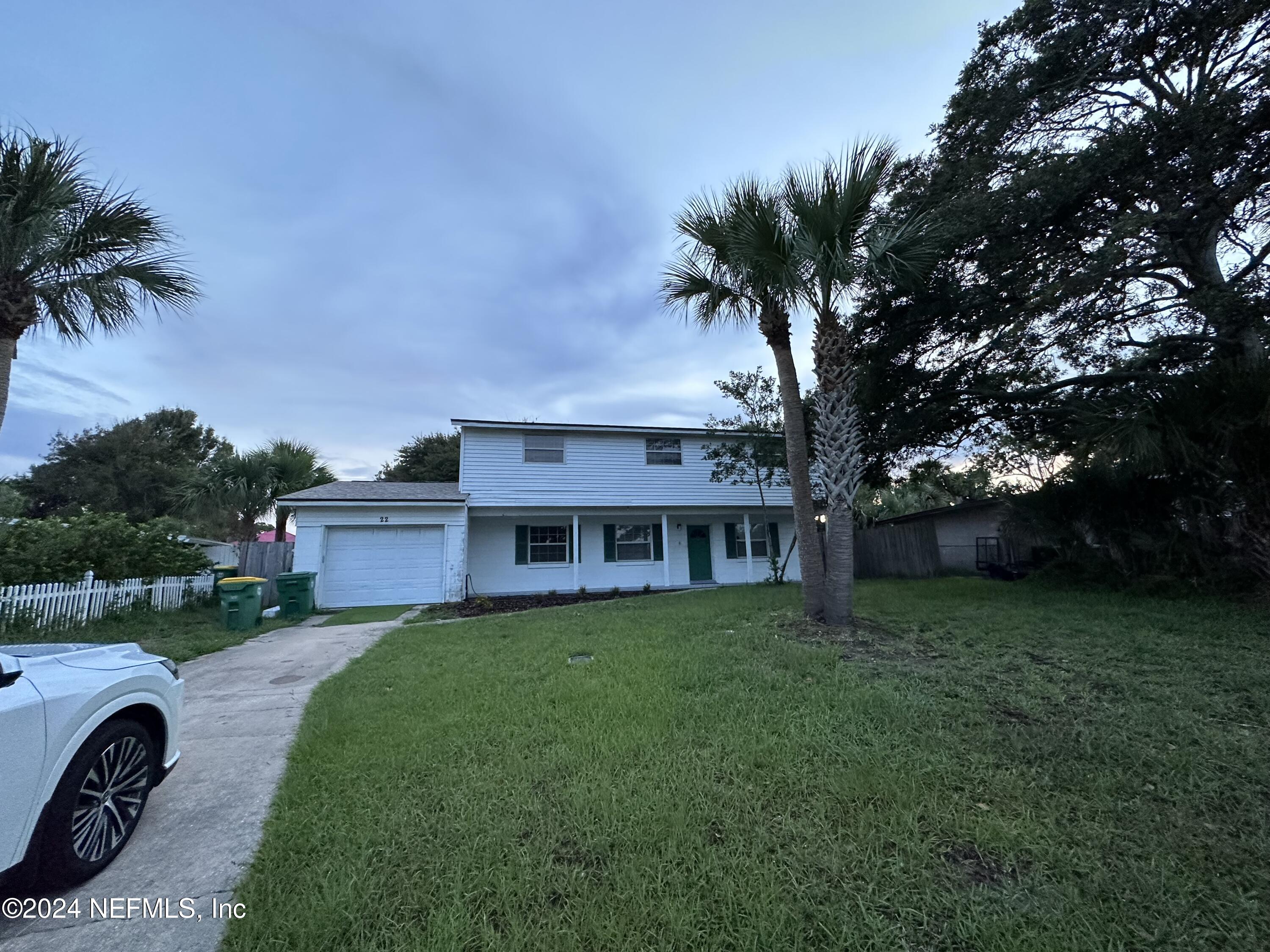 a view of a house with a big yard plants and palm trees