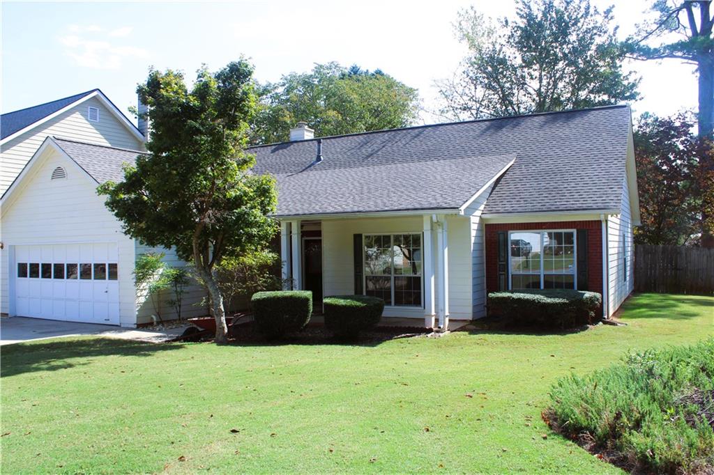 a view of a brick house with a yard plants and a large tree