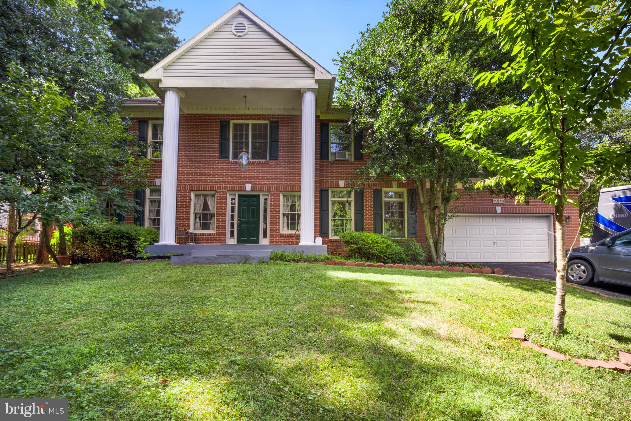 a view of a brick house with a yard and large tree