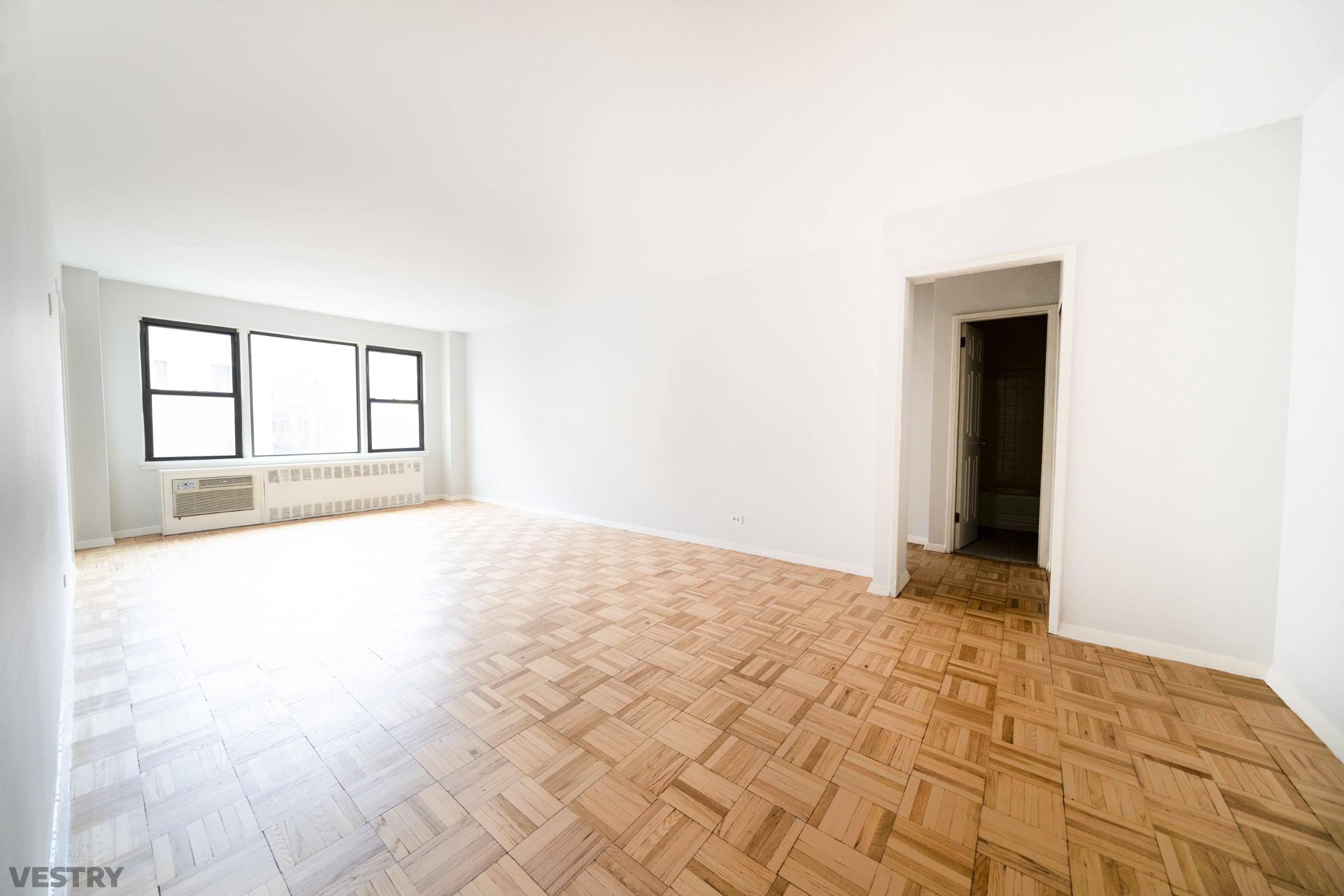 a view of an empty room with window and wooden floor