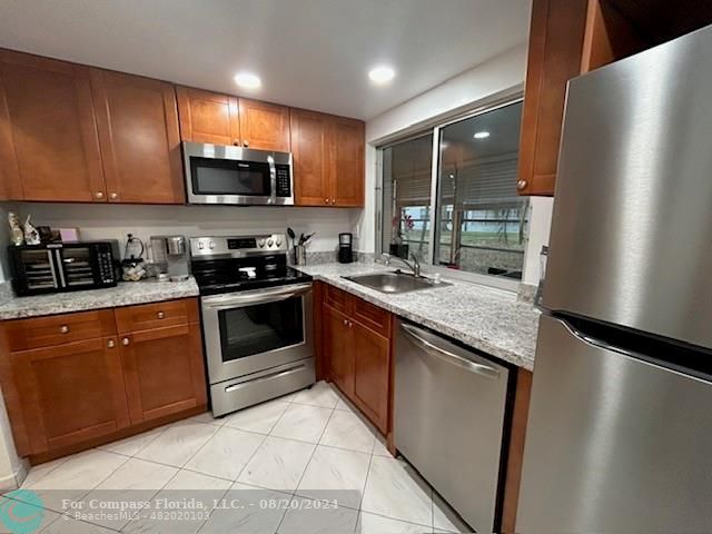 a large kitchen with stainless steel appliances granite countertop a stove a sink and a refrigerator