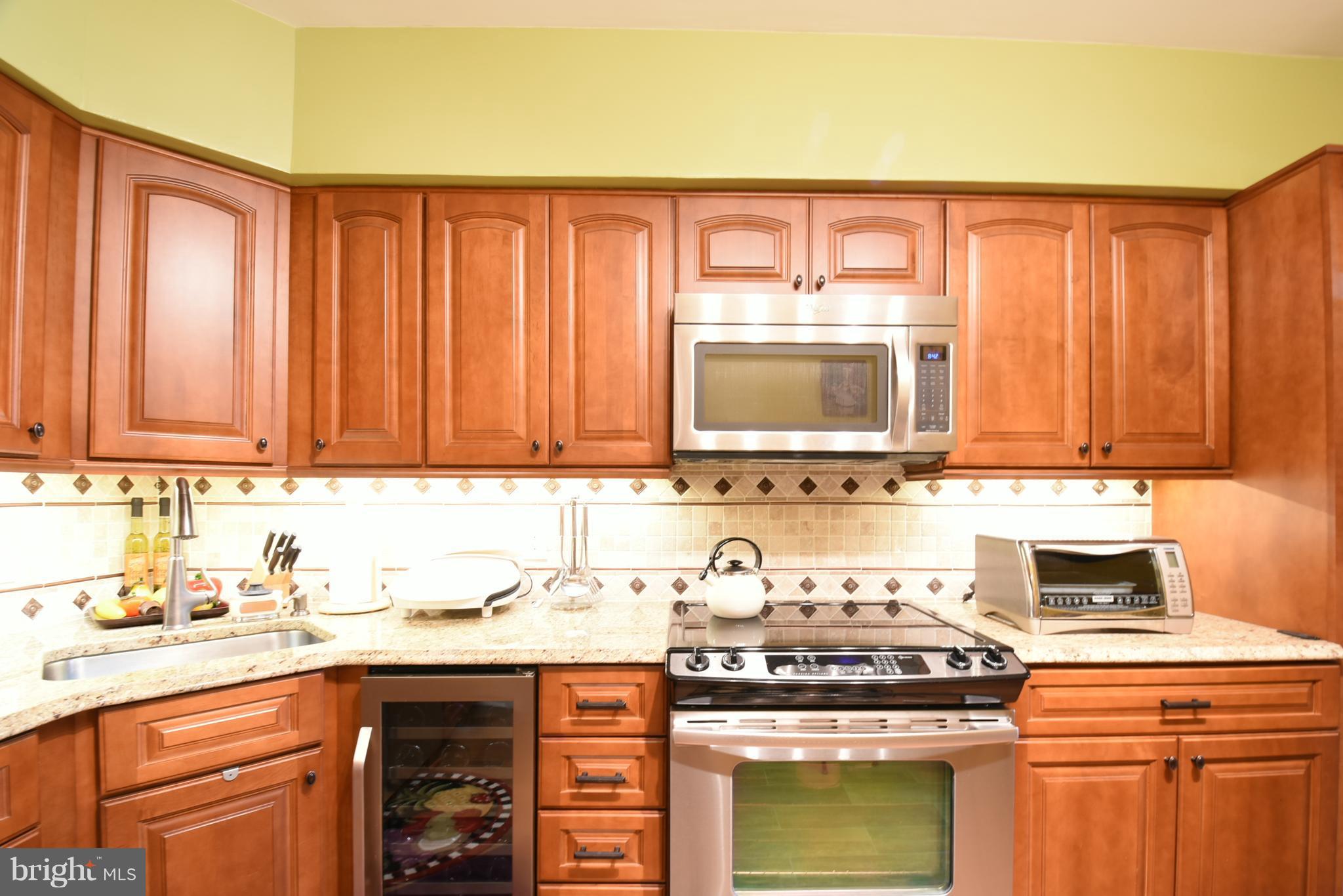 a kitchen with granite countertop a stove top oven cabinetry a sink and a microwave