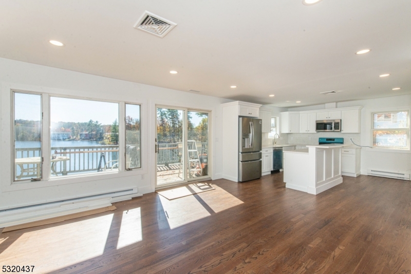 a living room with stainless steel appliances kitchen island wooden floor and a large window