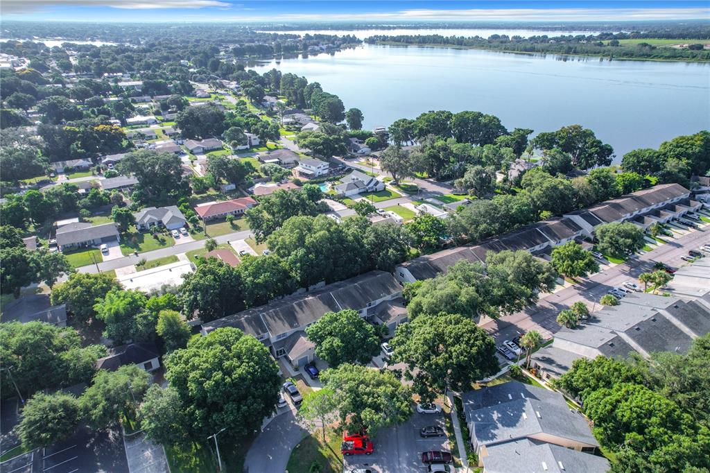 an aerial view of city and lake with trees all around