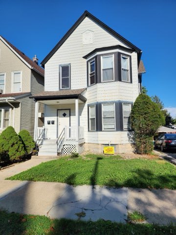 a front view of a house with a yard and potted plants