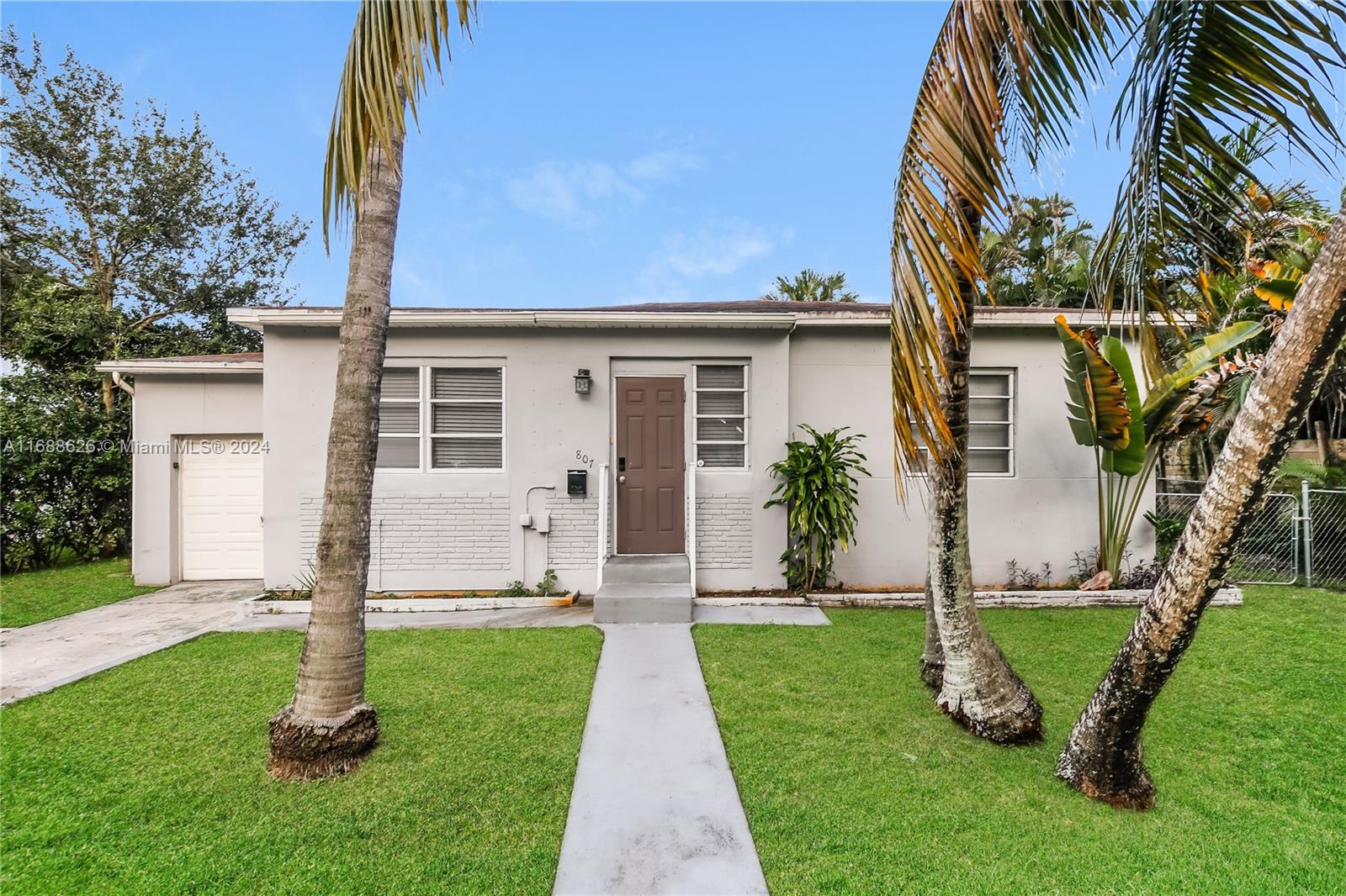 a view of a house with a yard and palm trees