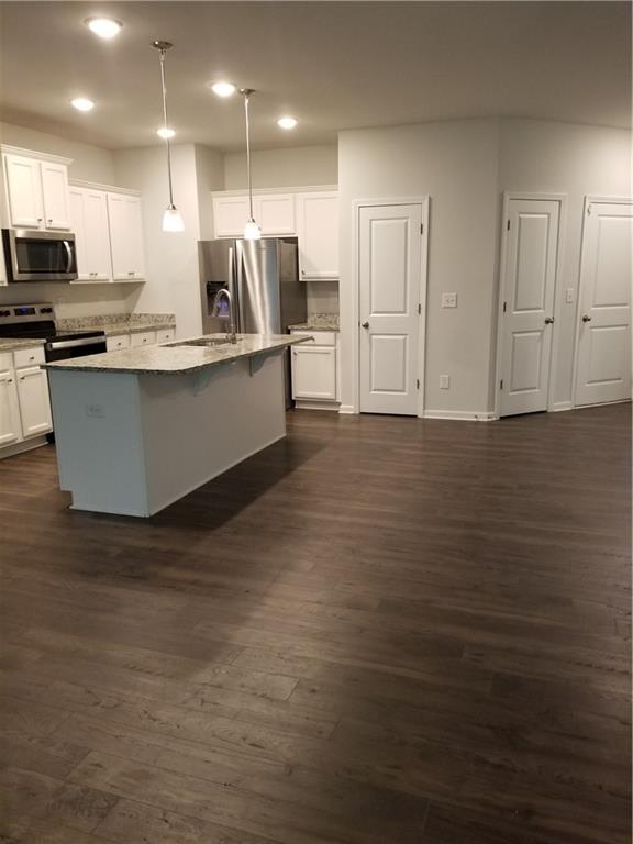 a view of kitchen with stainless steel appliances granite countertop stove top oven and cabinets