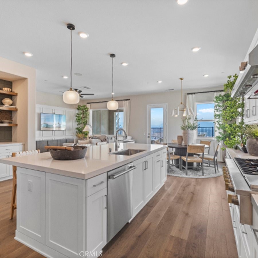 a kitchen with sink stove and white cabinets with wooden floor