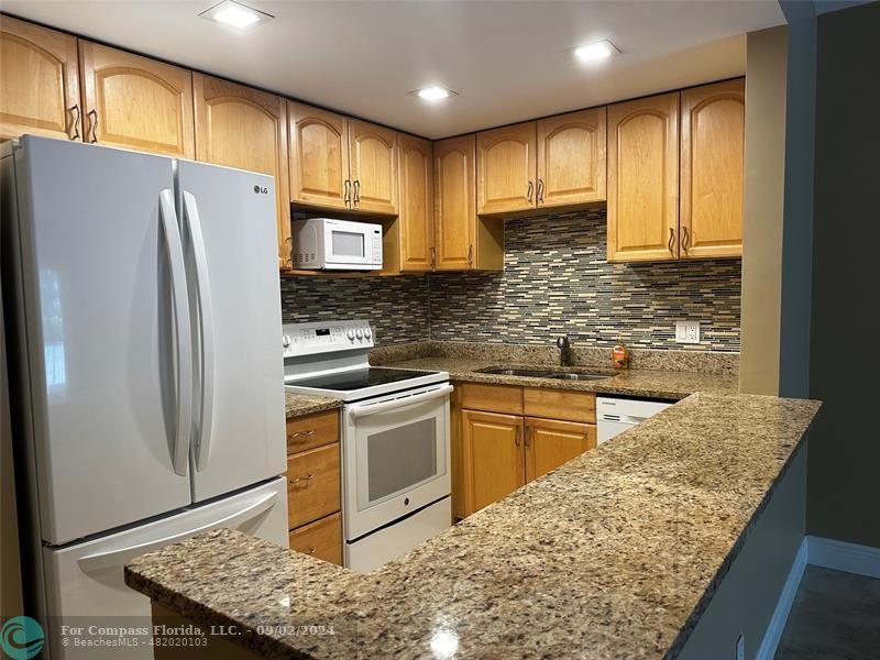 a kitchen with stainless steel appliances granite countertop a refrigerator sink and stove