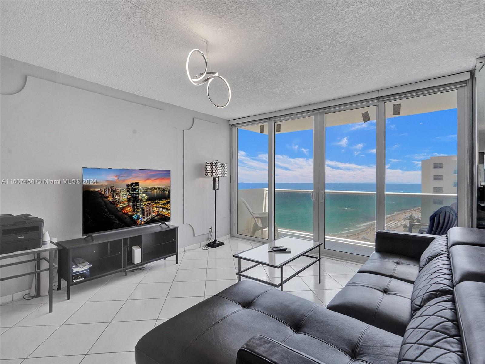 a living room with furniture a flat screen tv and a floor to ceiling window