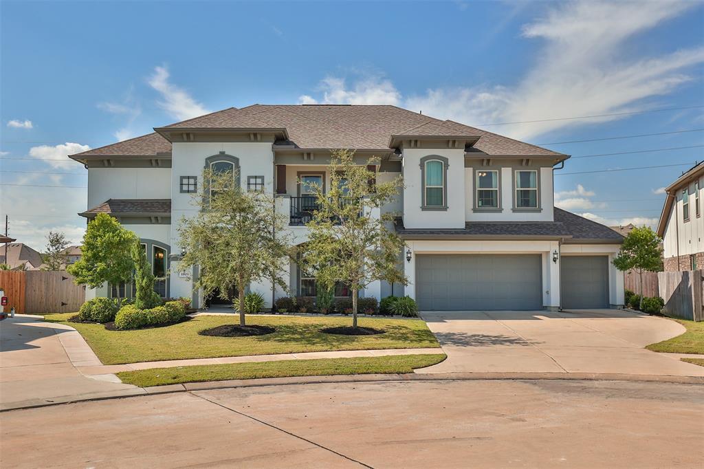 This is a spacious two-story home with a stucco and stone facade, featuring a three-car attached garage and a neatly landscaped yard. The property is located on a serene oversized premium cul de sac lot with plenty of room for guest parking