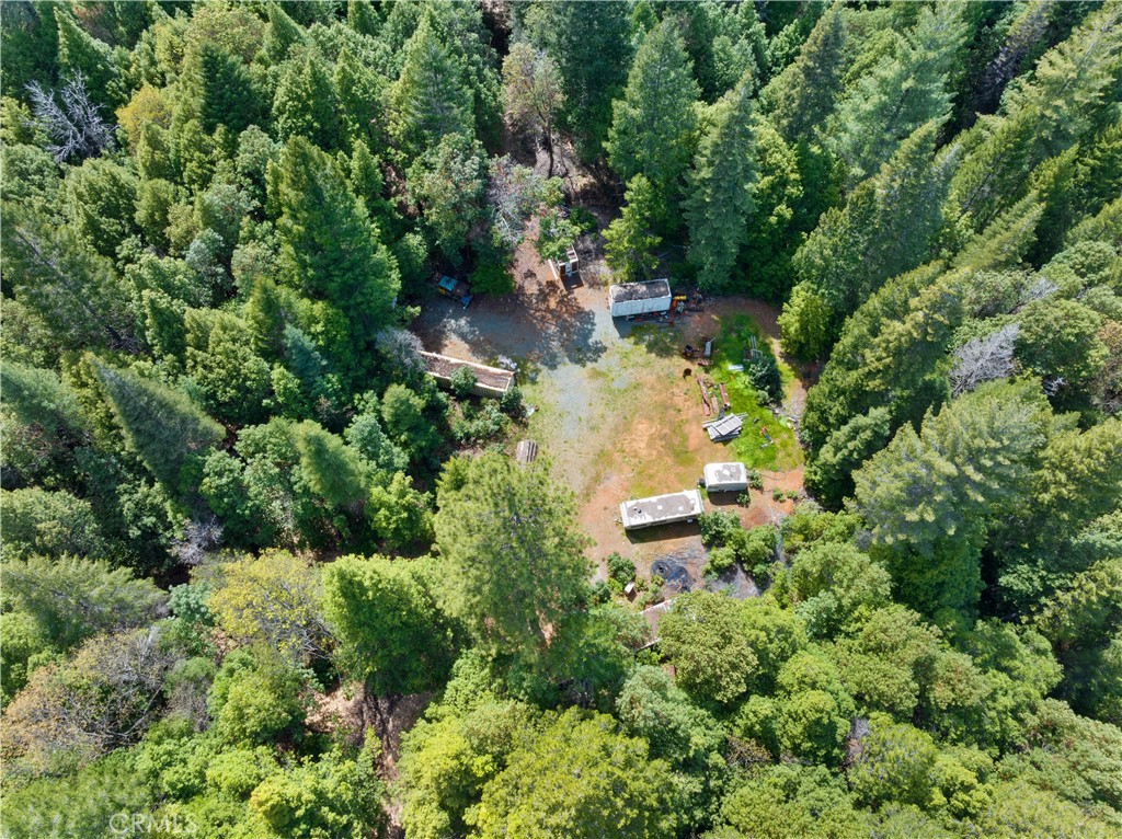 an aerial view of residential house with outdoor space and trees all around