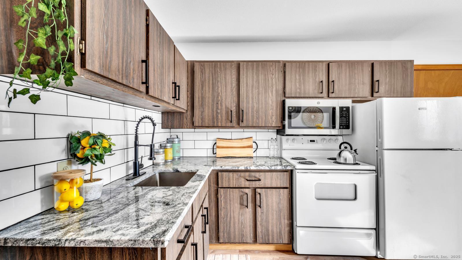 a kitchen with stainless steel appliances granite countertop a sink refrigerator and microwave