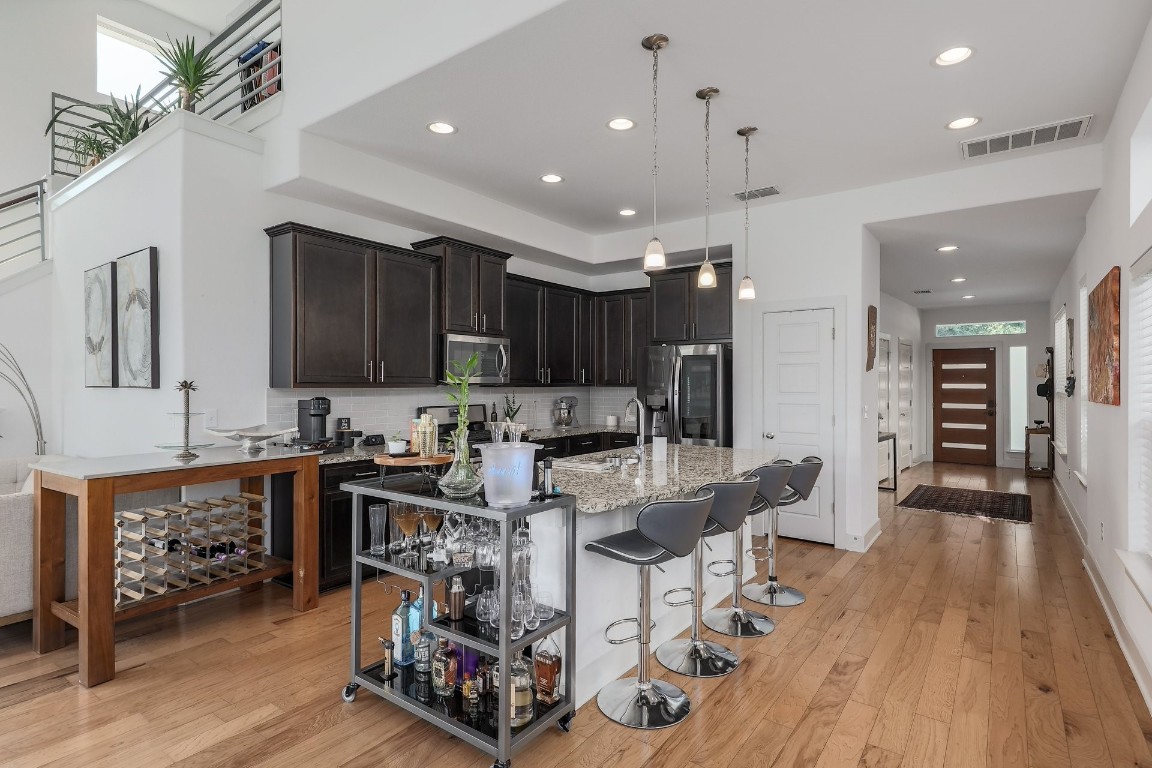 a living room with stainless steel appliances kitchen island granite countertop furniture wooden floor and a view of kitchen