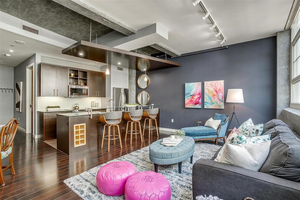 a living room with stainless steel appliances furniture a rug and a kitchen view