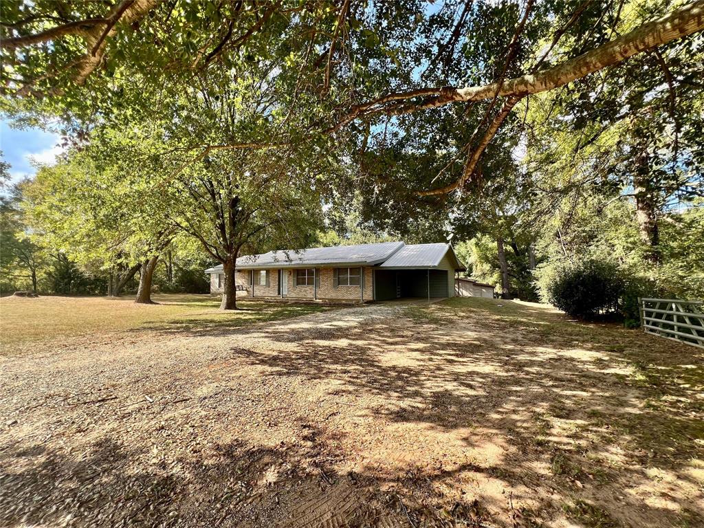 Charming single-story home nestled among mature trees on a spacious lot, offering a serene and private setting with ample yard space and a cozy, welcoming exterior.