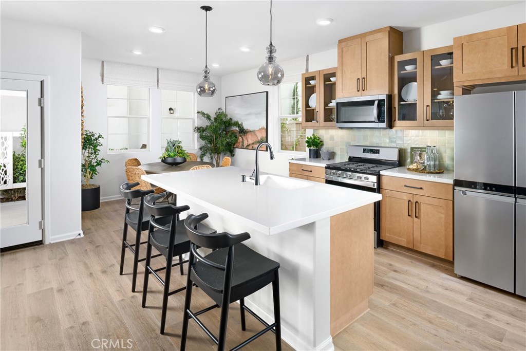 a kitchen with stainless steel appliances a white table chairs refrigerator and cabinets